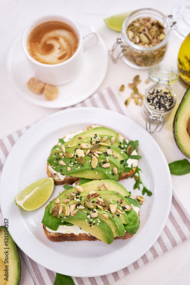 Freshly made Avocado and cream cheese toasts on a white ceramic plate and ingredients