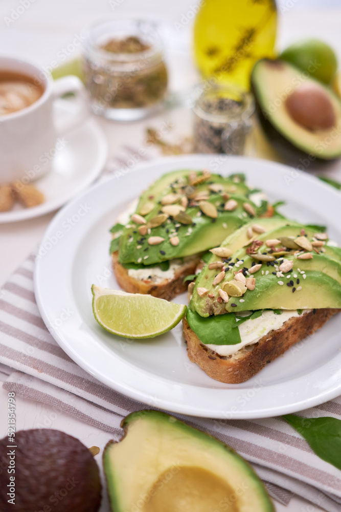 Freshly made Avocado and cream cheese toasts on a white ceramic plate and ingredients