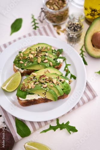 Freshly made Avocado and cream cheese toasts on a white ceramic plate and ingredients