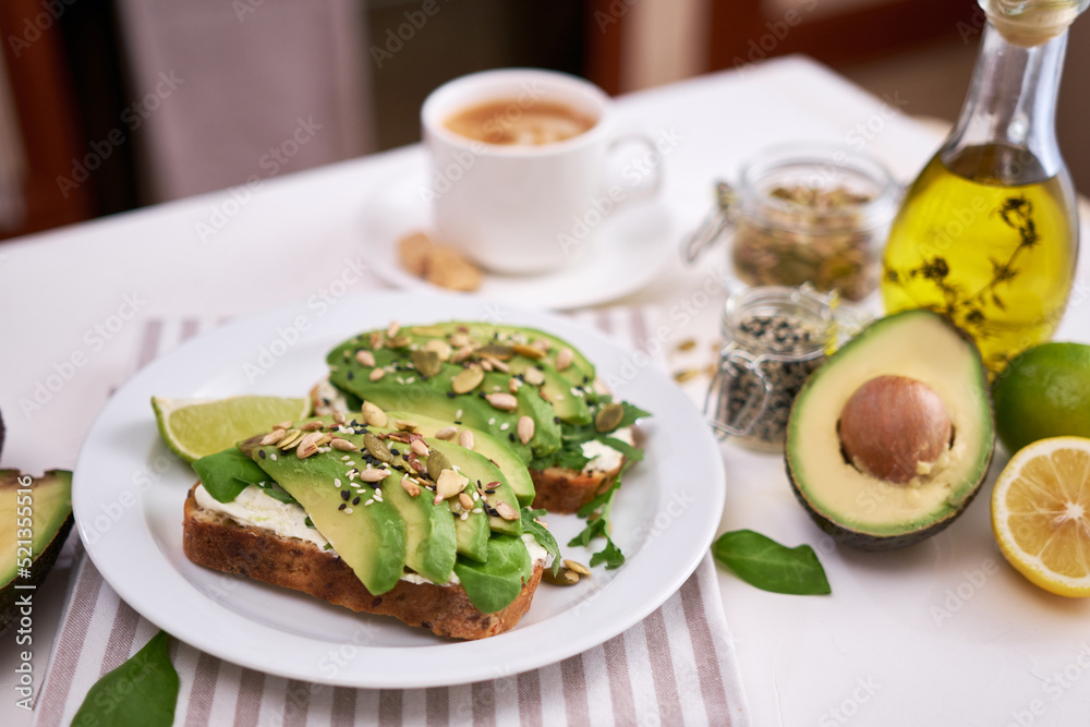 Freshly made Avocado and cream cheese toasts on a white ceramic plate and ingredients Freshly made Avocado and cream cheese toasts on a white ceramic plate and ingredients