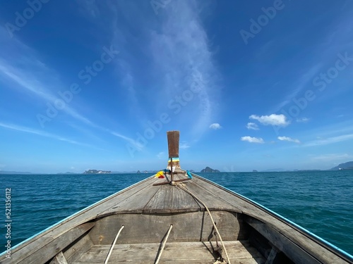 Bow's boat on the ocean ahead to island with beatiful clear blue sky and clouds.