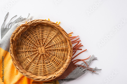 Autumn aesthetic concept. Top view photo of empty wicker basket and plaid on isolated white background