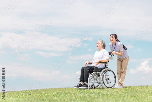 Fotografie, Tablou 公園を散歩する介護士と車椅子の高齢者女性（青空）