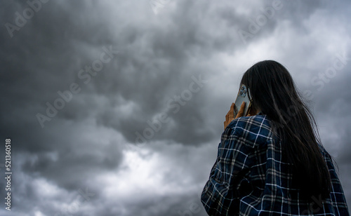 Beautiful asian woman with umbrella talking on the phone while raining and storm coming.Thunderstorm depression, Typhoon, Tornado.Dark cloud storm. Weather forecast outdoor .
