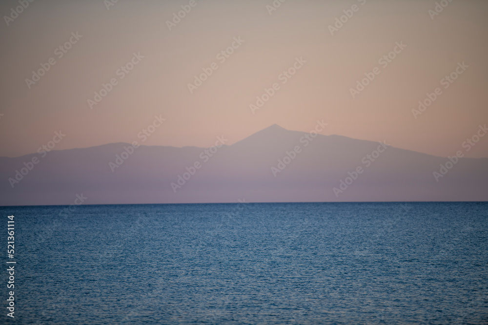 Beautiful landscape of mediterranean sea and mountains on the horizon at sunset. Blue water and orange sky.