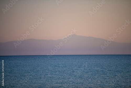 Beautiful landscape of mediterranean sea and mountains on the horizon at sunset. Blue water and orange sky.