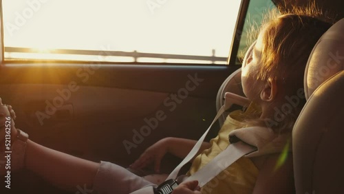 The child sits in a child car seat while the car is moving and looks out the window. Travel concept.