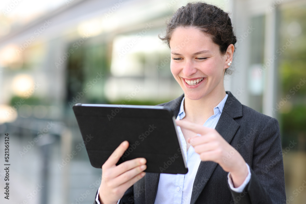 Happy executive using tablet walking in the street Happy executive using tablet walking in the street