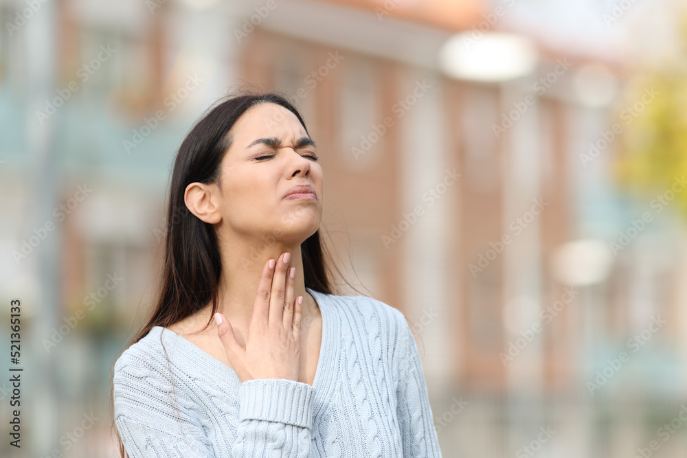 Stressed woman suffering sore throat in the street