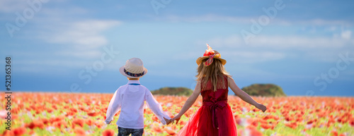 a boy and girl hold hands in the summer flowers field.