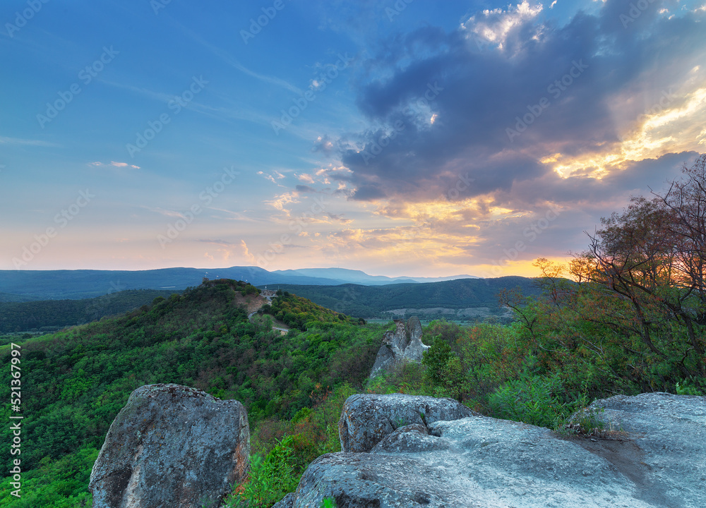 View from the mountain top at sunset with medieval castle ruins in the background on top of hill