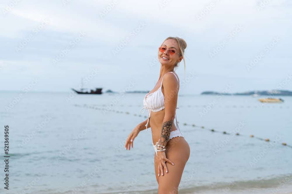 Young beautiful blonde woman in white cute bikini, orange stylish glasses and lace cape posing on beach,soft natural life, romantic, tender, woman in good shape, slim, sporty Young beautiful blonde woman in white cute bikini, orange stylish glasses and lace cape posing on beach,soft natural life, romantic, tender, woman in good shape, slim, sporty