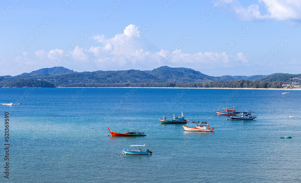 Beautiful seascape of Phuket island harbor in southern of thailand, fishing boat on blue sea with mountain view, water transportation