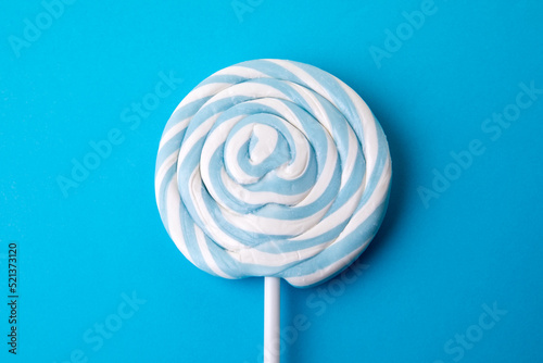 Round lollipop and blue background. Sweets and junk food