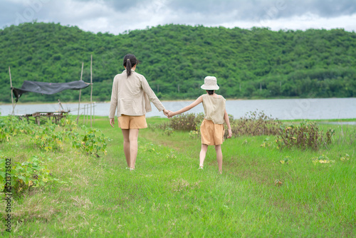 The mother and her daughter are holding hands and walking to the reservoir, enjoying vacation time at the Huai Phak Reservoir, Tha Yang District, Phetchaburi, Thailand.
