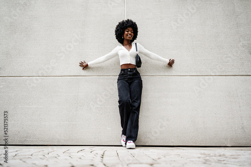 Fotografi Black woman with afro hair posing in front of a gray concrete wall