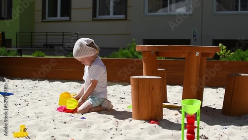 A girl is playing with shovels in the sandbox. High quality FullHD footage