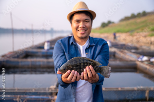 Aquaculture farmer hold quality tilapia yields in hand, guaranteeing integrity in organic bio-aquaculture. Fish is a high-quality protein food source. Commercial aquaculture in the Mekong River. photo