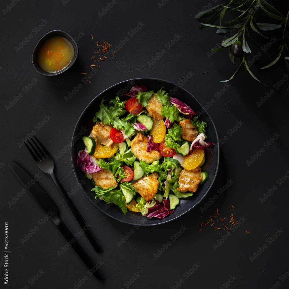 salad with chicken fillet, oranges, cherry tomatoes and lettuce leaves with sauce. Dark background, top view salad with chicken fillet, oranges, cherry tomatoes and lettuce leaves with sauce. Dark background, top view