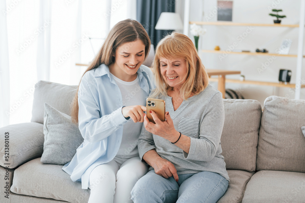 Using smartphone. Mother and daughter is together at home Using smartphone. Mother and daughter is together at home