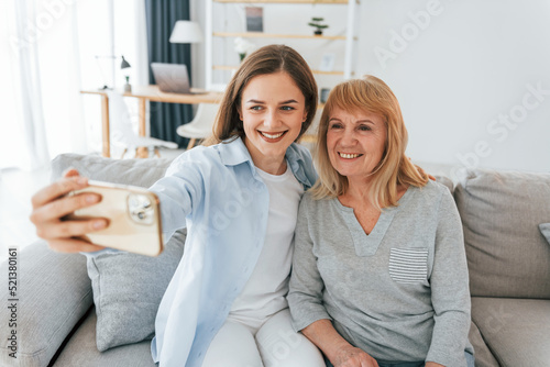 Making selfie by using smartphone. Mother and daughter is together at home photo