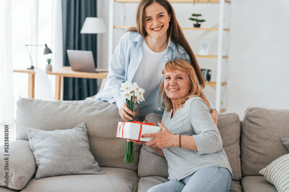 Flowers and present. Happy mother's day. Senior woman and daughter is together at home