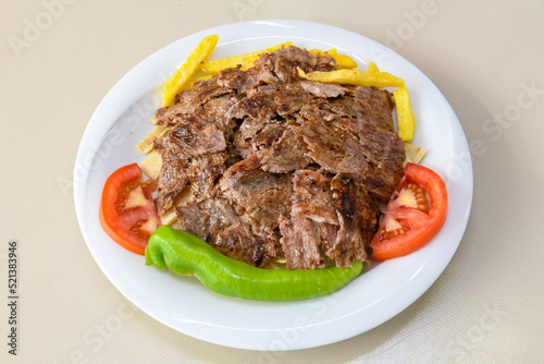 Turkish and Arabic Traditional Ramadan doner kebab with tasty tomato sauce and rice or turkish pilav in white plate on wood table background. ( Pilav ustu doner) © enderbayindir