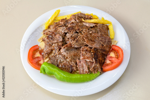 Turkish and Arabic Traditional Ramadan doner kebab with tasty tomato sauce and rice or turkish pilav in white plate on wood table background. ( Pilav ustu doner) photo