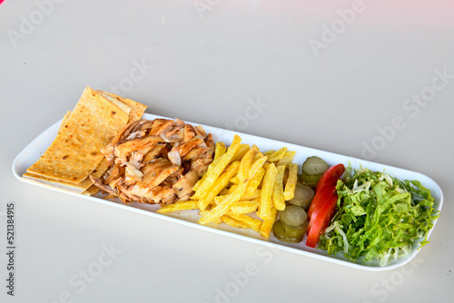 Turkish and Arabic Traditional Ramadan chicken doner kebab with tasty tomato sauce and rice or turkish pilav in white plate on wood table background. (Pilav ustu tavuk doner) photo