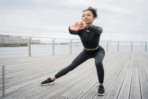 A confident woman working out on the street exercises for fitness, uses a smart watch for sports and an app for cardio counting © muse studio
