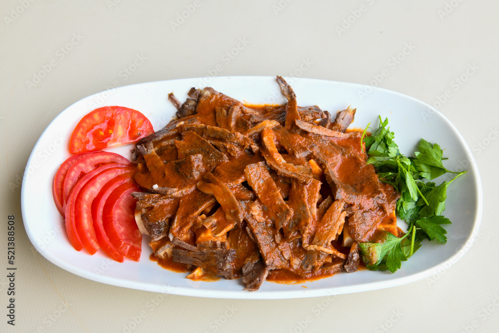 Turkish and Arabic Traditional Ramadan doner kebab with tasty tomato sauce and rice or turkish pilav in white plate on wood table background. ( Pilav ustu doner) Turkish and Arabic Traditional Ramadan doner kebab with tasty tomato sauce and rice or turkish pilav in white plate on wood table background. ( Pilav ustu doner)