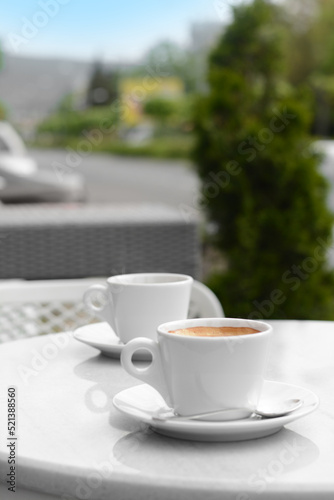 Ceramic cups of aromatic coffee with foam on table in morning