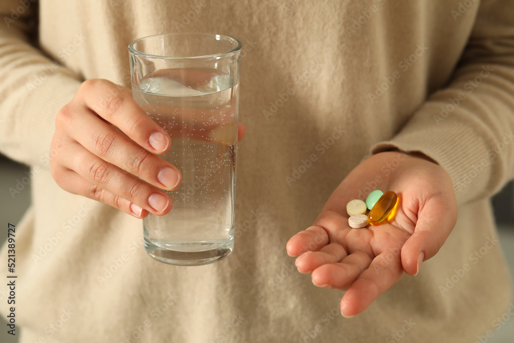 Young woman with glass of water and dietary supplement pills, closeup Young woman with glass of water and dietary supplement pills, closeup