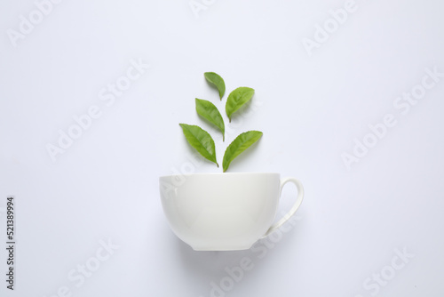 Fresh tea leaves and cup isolated on white