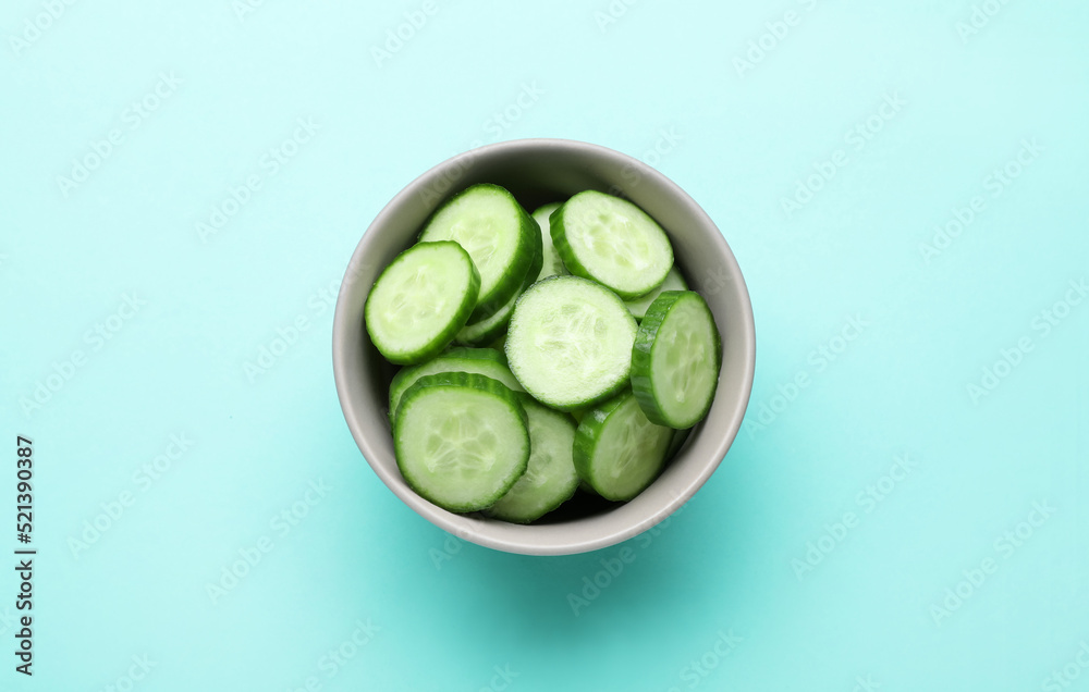 Slices of fresh ripe cucumber in bowl on light blue background, top view Slices of fresh ripe cucumber in bowl on light blue background, top view