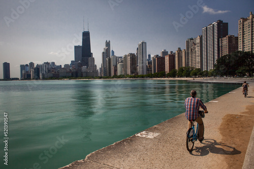 Two people riding bicycles by the Michigan Lake in North Ave Beach with Chicago skyline in the background