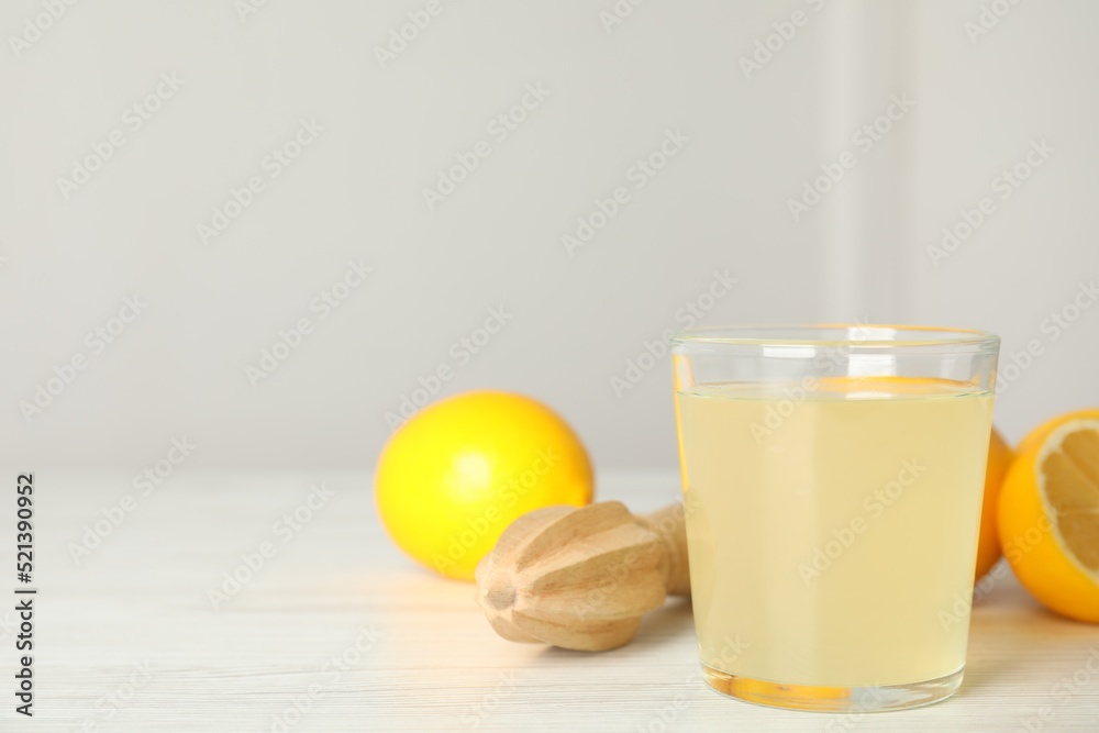 Freshly squeezed juice, lemons and reamer on white wooden table. Space for text Freshly squeezed juice, lemons and reamer on white wooden table. Space for text