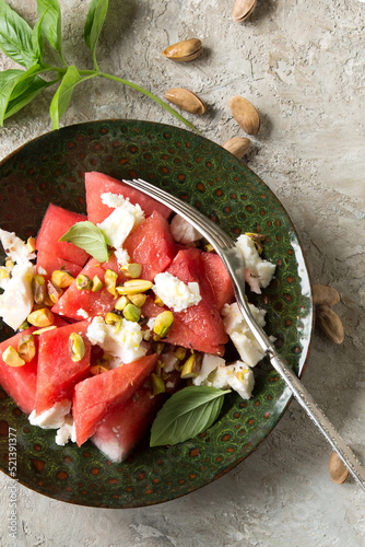 bowl with salad with watermelon, feta cheese and pistachios on the table