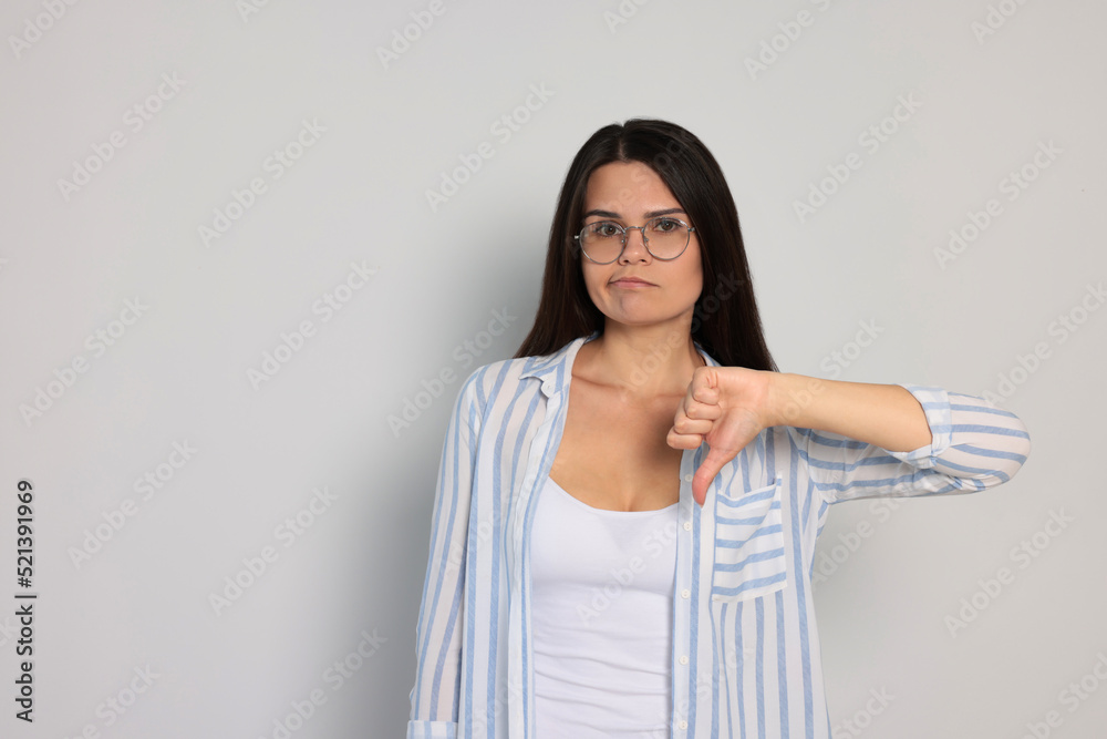 Young woman showing thumb down on white background, space for text Young woman showing thumb down on white background, space for text