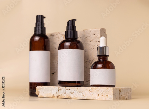 Brown glass cosmetic bottles on beige stone on light beige close up. label Mockup
