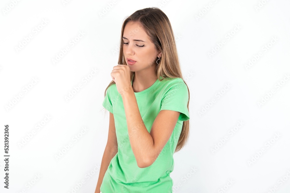 young beautiful woman wearing green T-shirt over white background, feeling unwell and coughing as symptom for cold or bronchitis. Healthcare concept. young beautiful woman wearing green T-shirt over white background, feeling unwell and coughing as symptom for cold or bronchitis. Healthcare concept.