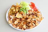 Turkish and Arabic Traditional Ramadan chicken doner kebab with tasty tomato sauce and rice or turkish pilav in white plate on wood table background. (Pilav ustu tavuk doner)