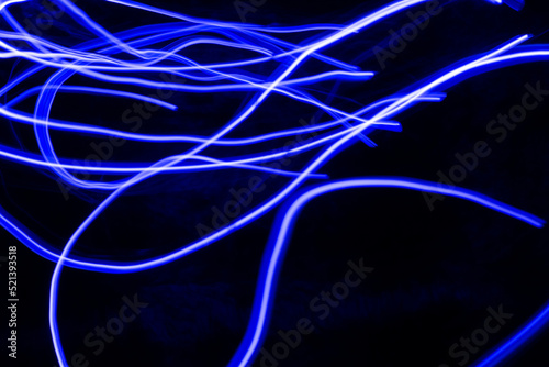 Full frame abstract image of blue neon light trails against black background © ivan
