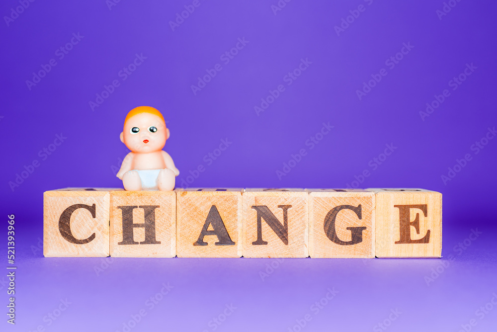 Φωτογραφία text the word shange from wooden letters,on the letter sits a miniature toy baby