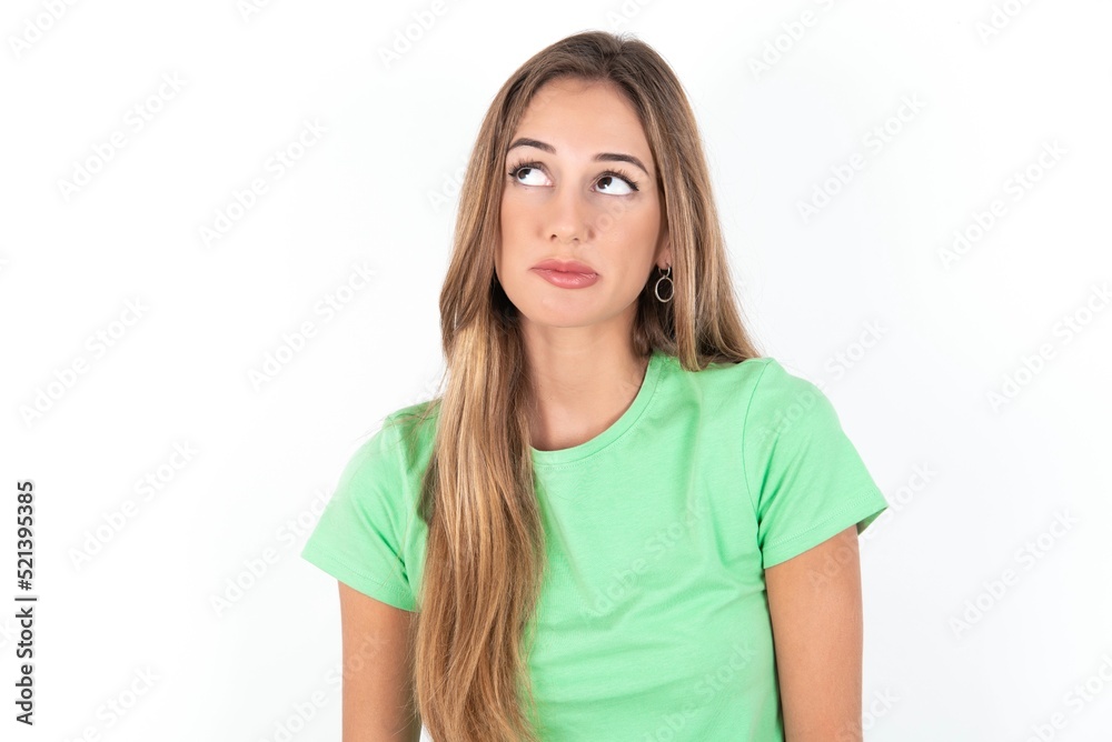 young beautiful woman wearing green T-shirt over white background, making grimace and crazy face, screaming out of control, funny lunatic expressing freedom and wild. young beautiful woman wearing green T-shirt over white background, making grimace and crazy face, screaming out of control, funny lunatic expressing freedom and wild.