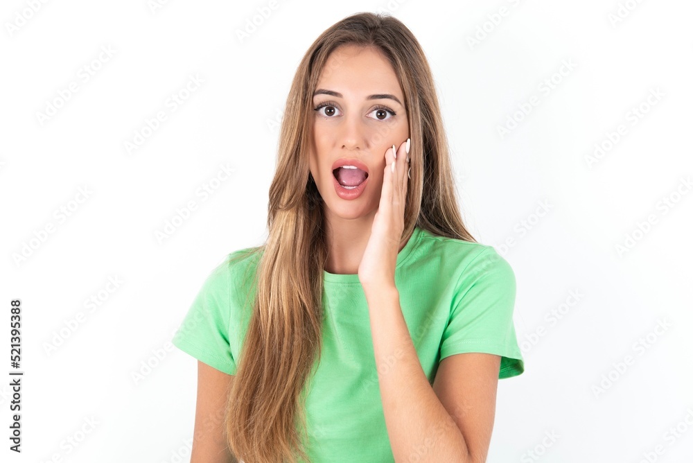 Shocked young beautiful woman wearing green T-shirt over white background, looks with great surprisment being very stunned, astonished with unexpected news, Facial expressions concept. Shocked young beautiful woman wearing green T-shirt over white background, looks with great surprisment being very stunned, astonished with unexpected news, Facial expressions concept.