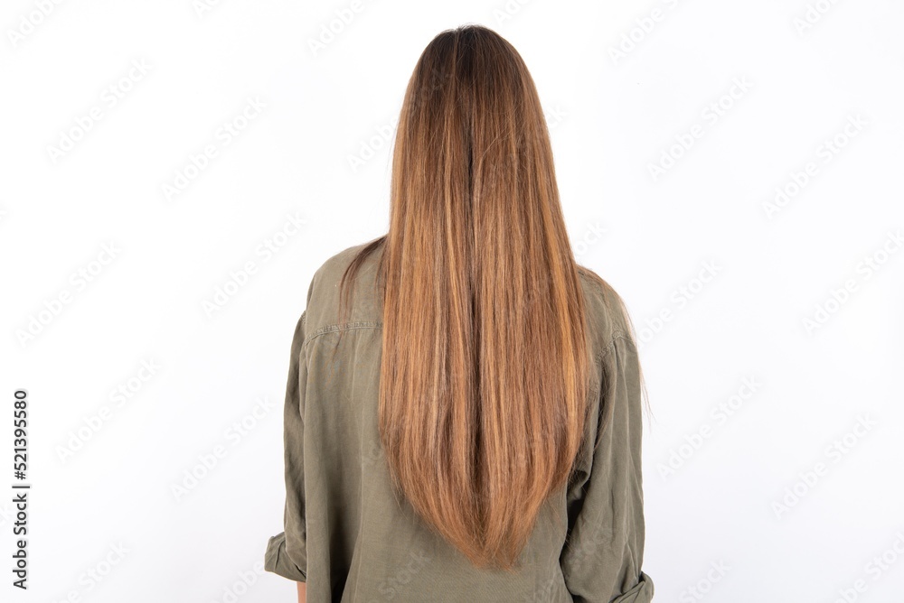 Naklejka premium The back view of a young beautiful woman wearing green overshirt over white background. Studio Shoot.
