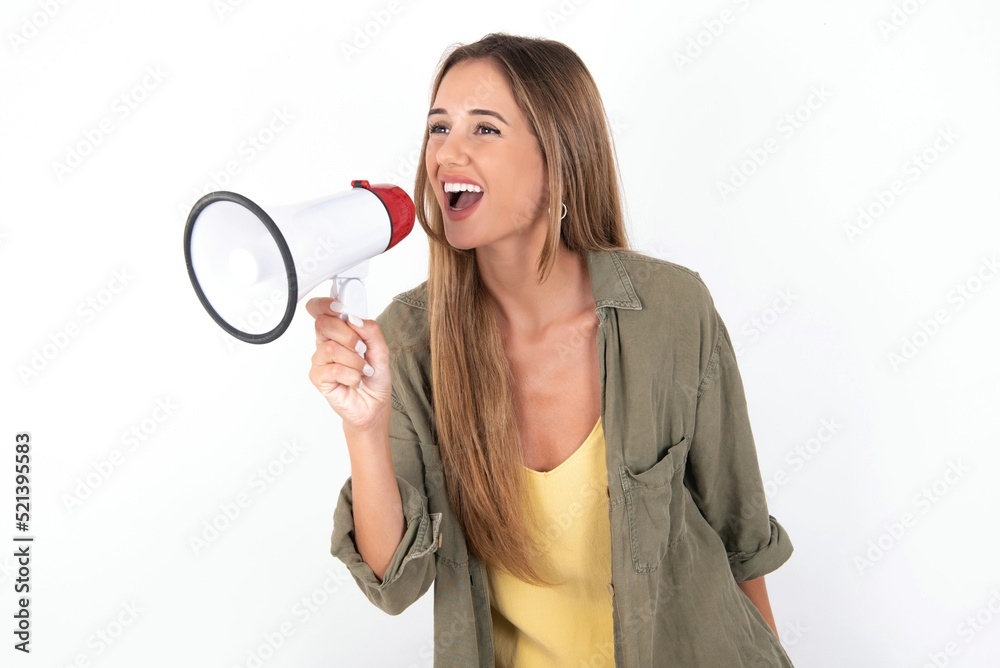 young beautiful woman wearing green overshirt over white background Through Megaphone with Available Copy Space young beautiful woman wearing green overshirt over white background Through Megaphone with Available Copy Space