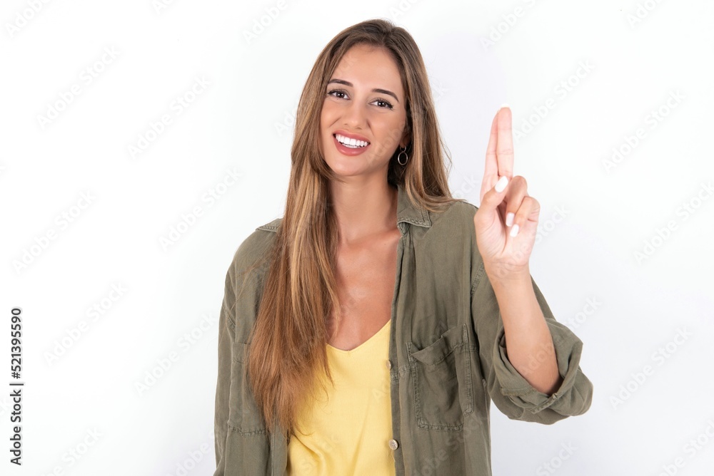 young beautiful woman wearing green overshirt over white background pointing up with fingers number ten in Chinese sign language Shi young beautiful woman wearing green overshirt over white background pointing up with fingers number ten in Chinese sign language Shi