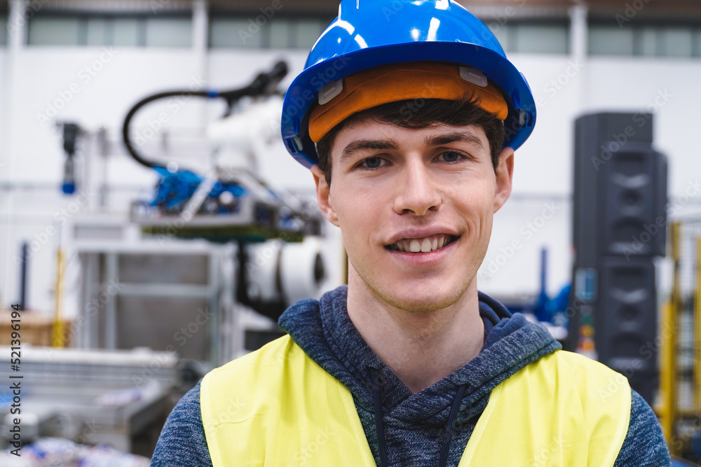 Young engineer working inside automation and robotics facility - Industrial tech concept - Focus on face